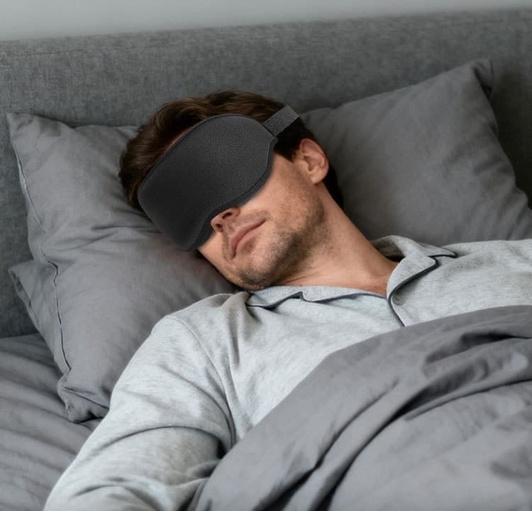 A man sleeping restfully on his back wearing the NightVeil sleep mask